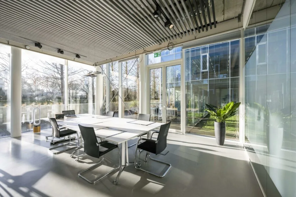 Moderne vergaderruimte aan de Fred. Roeskestraat met veel daglicht, glazen wanden en uitzicht op een groene binnenplaats.